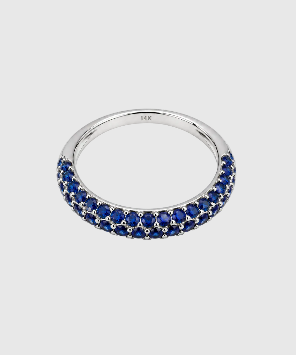 A silver band ring featuring a double row of round-cut deep blue sapphires, photographed on a clean white background. The inside of the band is engraved with '14K'.
