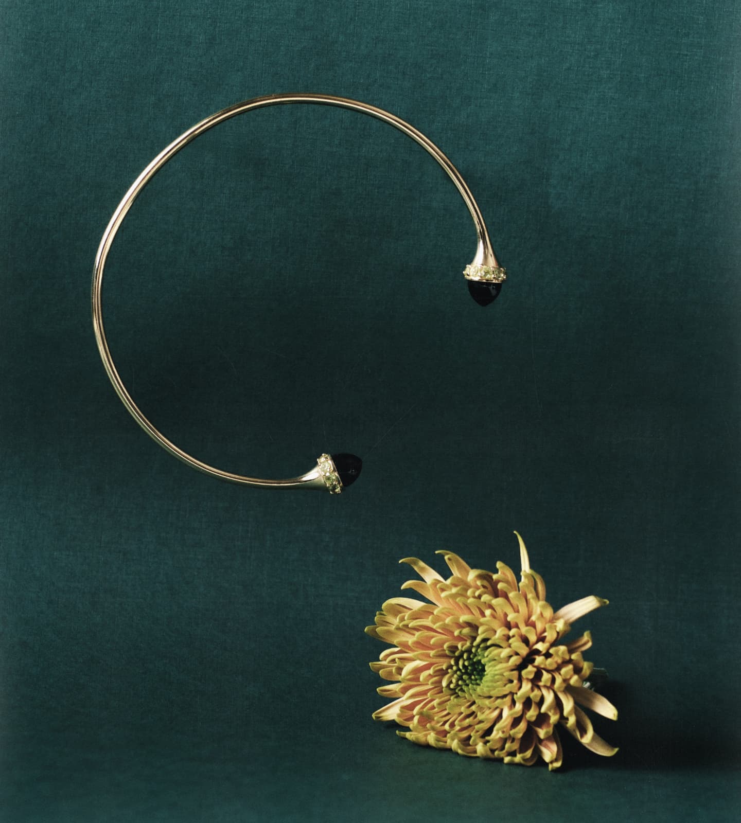 Silver necklace with floral design on a dark green background