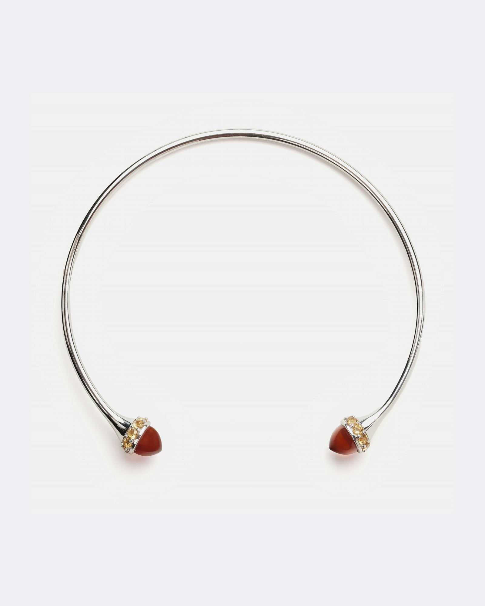 A silver-toned open cuff bangle bracelet with small heart-shaped red gemstones and tiny clear stones at the ends, shown on a plain white background.