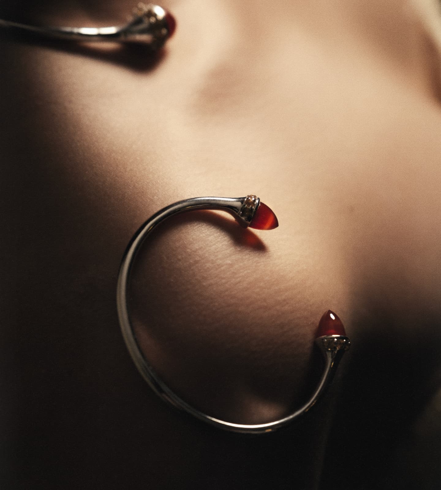 Silver hoop earrings with red gemstones on a dark background