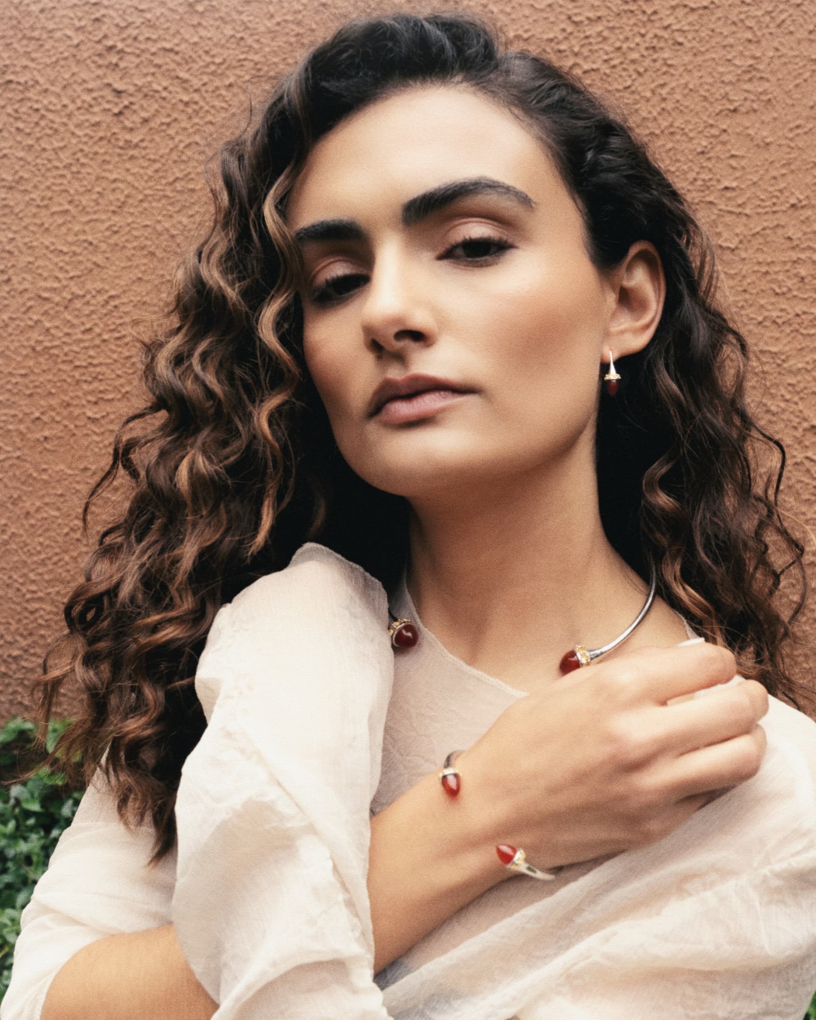 Woman wearing jewelry against a brown wall