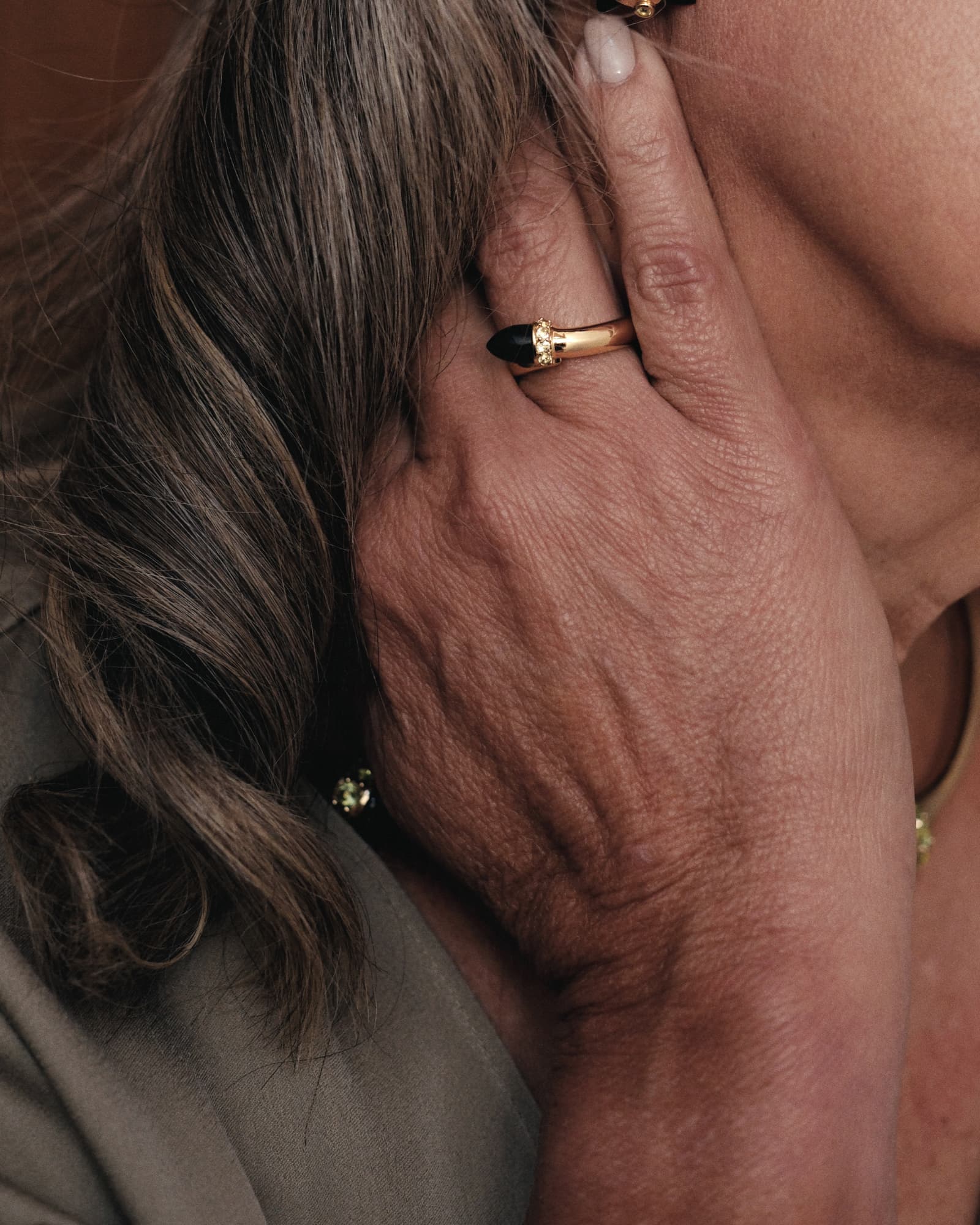 Close-up of a hand with a gold ring on a neutral background