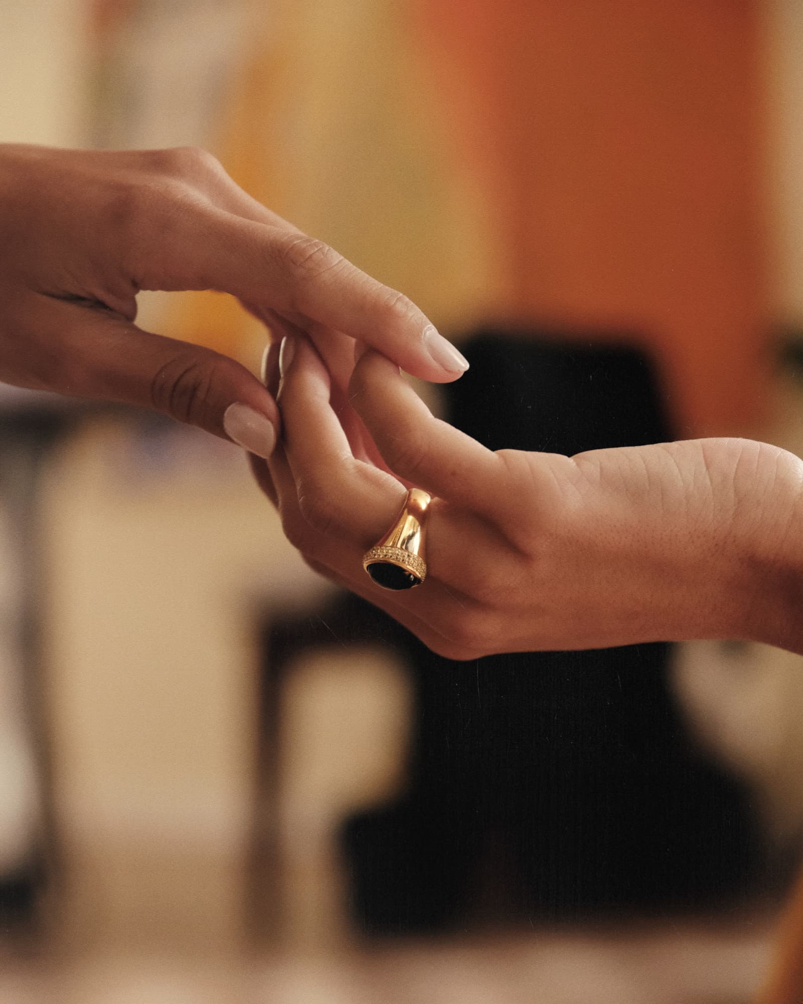 Close-up of a hand placing a ring on another hand with a blurred background