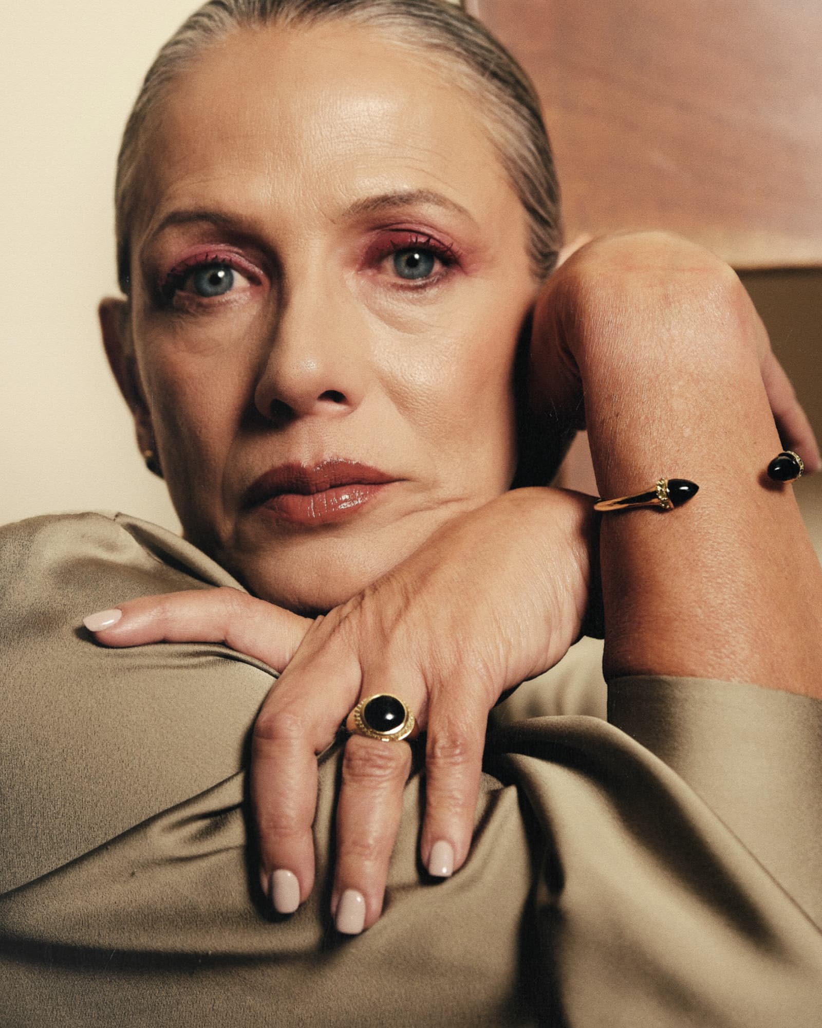 Woman with gray hair wearing a ring and bracelet, resting her head on her hand.