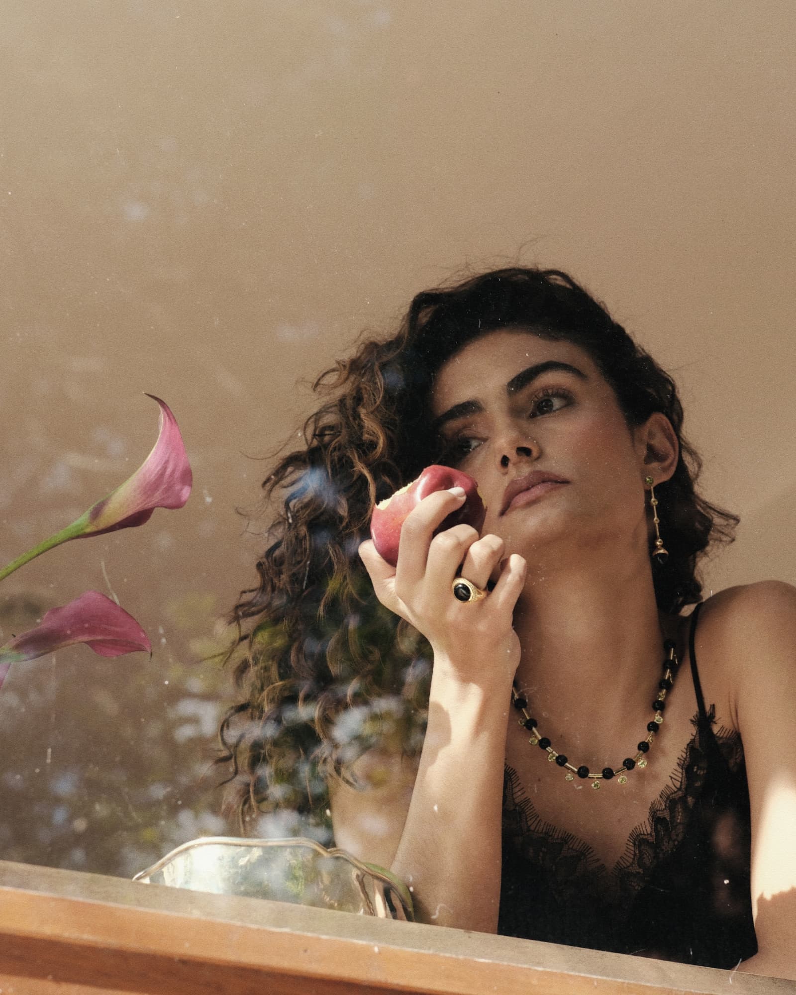 Woman holding a pink flower and an apple with a blurred background