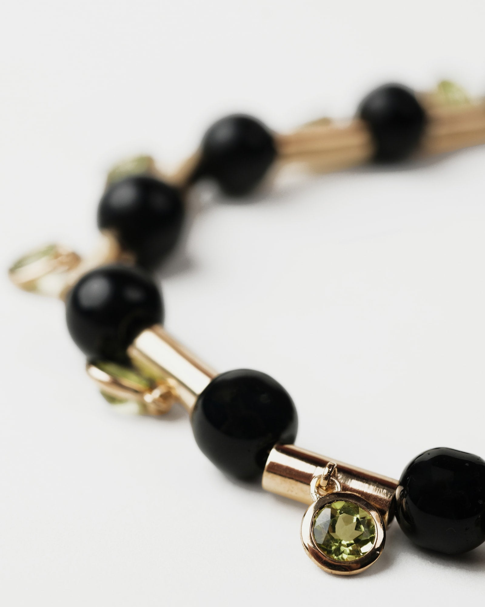 Bracelet with black beads and a green gemstone on a white background