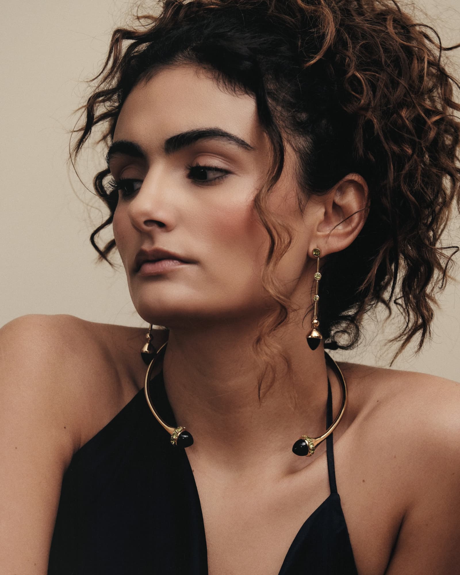 Woman wearing gold hoop earrings and a black top against a neutral background